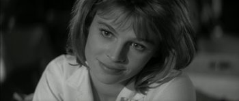 Movie still from “Billy Liar” (1963), directed by John Schlesinger – Black and white photograph of a young woman smiling for the camera; Close Up shot, Low angle