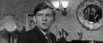 Movie still from “Billy Liar” (1963), directed by John Schlesinger – Black and white photograph of a man in a suit and tie; Close Up shot, Low angle
