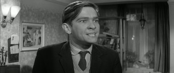 Movie still from “Billy Liar” (1963), directed by John Schlesinger – A black and white photo of a man wearing a suit and tie; Close Up shot, Low angle
