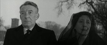 Movie still from “Billy Liar” (1963), directed by John Schlesinger – An older man and a younger woman standing next to each other; Close Up shot, Low angle