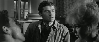 Movie still from “Billy Liar” (1963), directed by John Schlesinger – Black and white photograph of a man in a suit and tie; Close Up shot, Over the shoulder angle