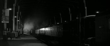 Movie still from “Billy Liar” (1963), directed by John Schlesinger – A black and white photo of a train at a station; Extreme Wide shot, High angle