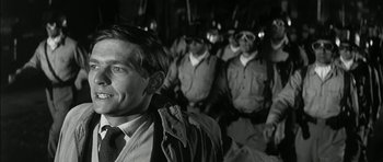 Movie still from “Billy Liar” (1963), directed by John Schlesinger – Black and white photograph of a man in front of a group of soldiers; Close Up shot, Low angle