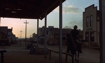 Movie still from “Billy Two Hats” (1974), directed by Ted Kotcheff – A man riding a horse through a dirt field; Wide shot, Low angle