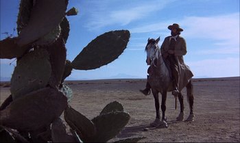 Movie still from “Billy Two Hats” (1974), directed by Ted Kotcheff – A man on a horse in the desert; Wide shot, Low angle
