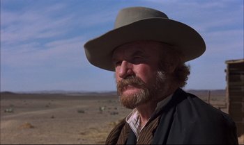 Movie still from “Billy Two Hats” (1974), directed by Ted Kotcheff – A man with a long beard wearing a cowboy hat; Close Up shot, Low angle