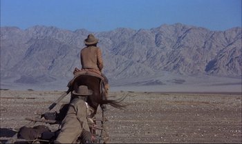 Movie still from “Billy Two Hats” (1974), directed by Ted Kotcheff – A man riding a horse in the middle of the desert; Extreme Wide shot, Low angle