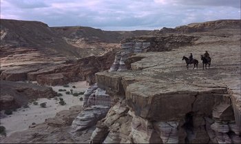 Movie still from “Billy Two Hats” (1974), directed by Ted Kotcheff – A man riding a horse on top of a rock formation; Extreme Wide shot, High angle
