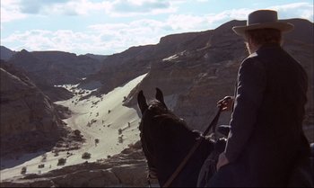 Movie still from “Billy Two Hats” (1974), directed by Ted Kotcheff – A person riding a horse on top of a mountain; Wide shot, High angle