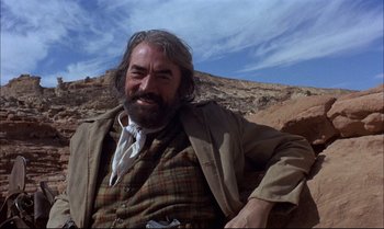 Movie still from “Billy Two Hats” (1974), directed by Ted Kotcheff – A man with long hair and a beard is smiling; Medium shot, Low angle