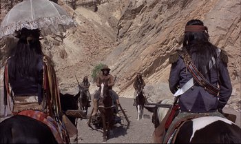 Movie still from “Billy Two Hats” (1974), directed by Ted Kotcheff – A group of people on horses on a dirt road; Wide shot, High angle