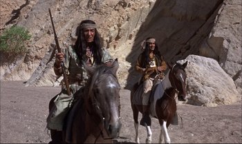 Movie still from “Billy Two Hats” (1974), directed by Ted Kotcheff – Two native american men riding horses in the desert; Wide shot, Low angle