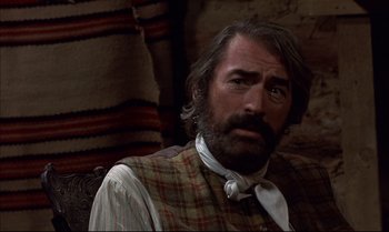 Movie still from “Billy Two Hats” (1974), directed by Ted Kotcheff – A person sitting on a couch; Close Up shot, Over the shoulder angle