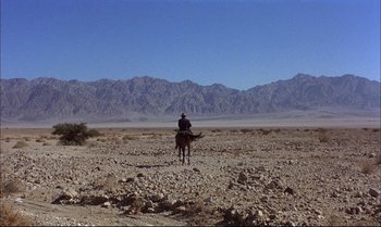 Movie still from “Billy Two Hats” (1974), directed by Ted Kotcheff – A man riding a horse in the desert; Extreme Wide shot, High angle
