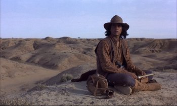Movie still from “Billy Two Hats” (1974), directed by Ted Kotcheff – A man sitting on the ground in the middle of the desert; Wide shot, Low angle