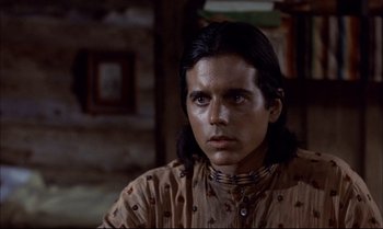 Movie still from “Billy Two Hats” (1974), directed by Ted Kotcheff – A man with long black hair wearing a brown shirt; Close Up shot, Low angle