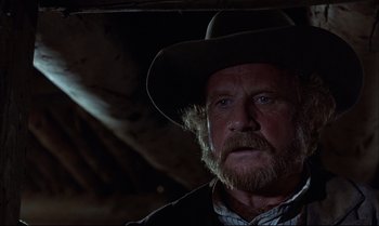 Movie still from “Billy Two Hats” (1974), directed by Ted Kotcheff – An old man with a beard wearing a cowboy hat; Close Up shot, Low angle