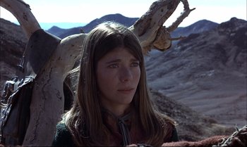 Movie still from “Billy Two Hats” (1974), directed by Ted Kotcheff – A young woman with long hair and a tree in the background; Close Up shot, Low angle