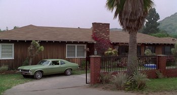 Movie still from “Bio-Dome” (1996), directed by Jason Bloom – A green car parked in front of a brown house; Wide shot, High angle