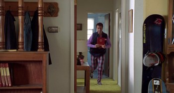 Movie still from “Bio-Dome” (1996), directed by Jason Bloom – A man is walking through a hallway holding a book; Wide shot, High angle