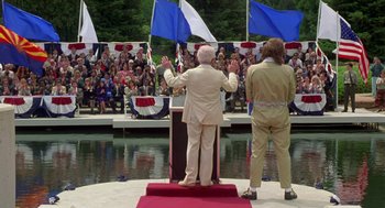 Movie still from “Bio-Dome” (1996), directed by Jason Bloom – Two men standing at a podium in front of an audience; Wide shot, High angle