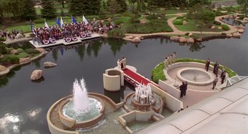 Movie still from “Bio-Dome” (1996), directed by Jason Bloom – A group of people standing around a pond with fountains; Extreme Wide shot, High angle