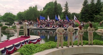 Movie still from “Bio-Dome” (1996), directed by Jason Bloom – A group of men standing on a bridge near a body of water; Wide shot, High angle