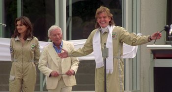Movie still from “Bio-Dome” (1996), directed by Jason Bloom – Two men standing next to each other in front of a microphone; Medium shot, Low angle