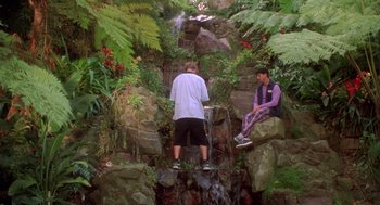 Movie still from “Bio-Dome” (1996), directed by Jason Bloom – Two young men sitting on rocks near a waterfall; Wide shot, Low angle