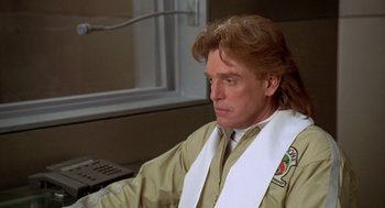 Movie still from “Bio-Dome” (1996), directed by Jason Bloom – A man with long blonde hair wearing a white stole; Close Up shot, Low angle