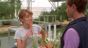 Movie still from “Bio-Dome” (1996), directed by Jason Bloom – A woman holding a bunch of carrots in her mouth; Medium shot, Over the shoulder angle