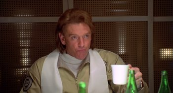 Movie still from “Bio-Dome” (1996), directed by Jason Bloom – A man in a tan jacket holding a white cup; Close Up shot, Low angle