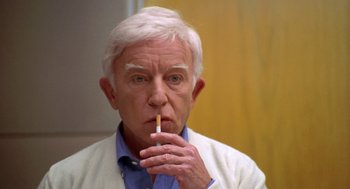 Movie still from “Bio-Dome” (1996), directed by Jason Bloom – An older man is holding a cigarette in his mouth; Close Up shot, Low angle