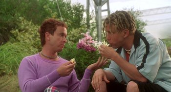 Movie still from “Bio-Dome” (1996), directed by Jason Bloom – A couple of men sitting next to each other eating food; Medium shot, Low angle