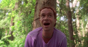 Movie still from “Bio-Dome” (1996), directed by Jason Bloom – A man in a purple shirt is by a tree; Close Up shot, Low angle
