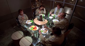Movie still from “Bio-Dome” (1996), directed by Jason Bloom – A group of people sitting around a table eating; Wide shot, High angle