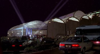 Movie still from “Bio-Dome” (1996), directed by Jason Bloom – Cars parked in front of a building at night; Extreme Wide shot, Low angle