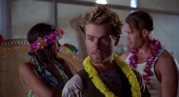 Movie still from “Bio-Dome” (1996), directed by Jason Bloom – A man wearing a yellow lei standing in front of other people; Close Up shot, Over the shoulder angle