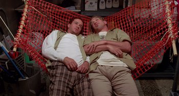 Movie still from “Bio-Dome” (1996), directed by Jason Bloom – A couple of men laying on top of a red hammock; Medium shot, Low angle