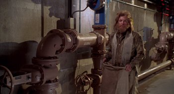 Movie still from “Bio-Dome” (1996), directed by Jason Bloom – A man standing in front of a pipe; Medium shot, Low angle