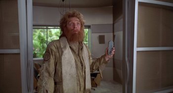 Movie still from “Bio-Dome” (1996), directed by Jason Bloom – A man with long hair and a red beard holding a cell phone; Medium shot, Low angle
