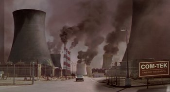 Movie still from “Bio-Dome” (1996), directed by Jason Bloom – A car driving down a street near a power plant; Extreme Wide shot, High angle