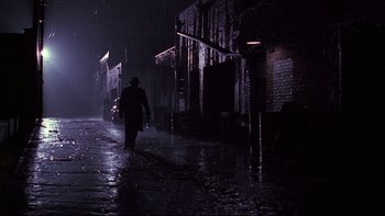 Movie still from “Bird” (1988), directed by Clint Eastwood – A man walking down the street in the dark; Wide shot, Low angle