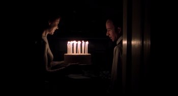 Movie still from “Birth” (2004), directed by Jonathan Glazer – A man and a woman looking at a cake with lit candles on it; Medium shot, Over the shoulder angle