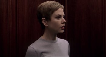 Movie still from “Birth” (2004), directed by Jonathan Glazer – A woman with short blonde hair wearing a gray shirt; Close Up shot, Low angle