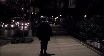 Movie still from “Birth” (2004), directed by Jonathan Glazer – A person walking down a sidewalk at night; Wide shot, Over the shoulder angle
