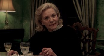 Movie still from “Birth” (2004), directed by Jonathan Glazer – An older woman sitting at a table with a glass of water; Close Up shot, Over the shoulder angle