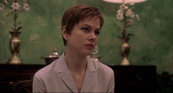 Movie still from “Birth” (2004), directed by Jonathan Glazer – A woman with short brown hair sitting in front of a green wall; Close Up shot, Over the shoulder angle