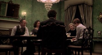 Movie still from “Birth” (2004), directed by Jonathan Glazer – A group of people sitting around a table; Medium shot, Over the shoulder angle