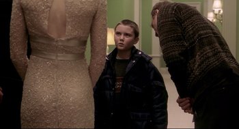 Movie still from “Birth” (2004), directed by Jonathan Glazer – A young boy standing next to a man in a dress; Medium shot, Over the shoulder angle